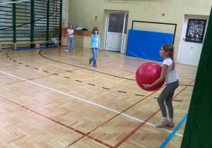 Uczennice na sali gimnastycznej podczas gry dużą połką.