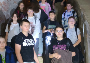 Zwiedzanie Twierdzy Modlin. Uczniowie klas IV-VIII z uśmiechami na twarzy stoją na schodach, pozując do zdjęcia