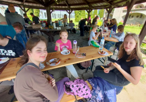 Chwila relaksu, uczniowie jedzą kiełbaski z ogniska, które wcześnie sami upiekli. Widząc ich uśmiechnięte twarze to podobało im się to pieczenie kiełbasek.