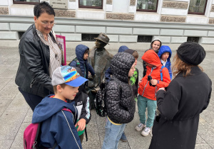Zbiórka pod Urzędem Miasta Łodzi uczniów klasy pierwszej. Stoimy z Panią Katarzyną Zielińską, która opowiada o historii budynku, którym mieści się urząd.