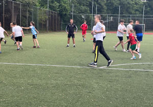 Uczniowie rozgrzewają się przed meczem na pobliskim boisku. Wszyscy ćwiczą z zaangażowaniem i uśmiechem.