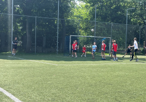 Mecz w toku. Akcja pod bramką. Uczniowie ustawieni, tak aby padł pierwszy gol.