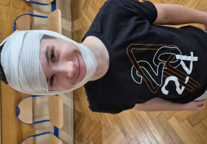 Uśmiechnięty uczeń klasy ósmej z opatrzoną głową