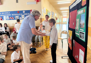 Przewodniczący klasy V odpiera nagrodę i dyplom dla swojej klasy w związku z najlepszym wynikiem w akcji Samorządu Uczniowskiego ,,Aktywna klasa"