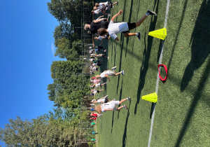 Rozgrzewka przed zawodami. Uczniowie biegają po wyznaczonej części boiska.