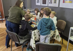 Uczniowie klasy IV uważnie słuchają pani prowadzącej warsztaty jak tkać i co należy sobie przygotować.