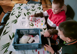 Chłopcy z klasy VI z ciekawością przyglądają się różnym tkaninom