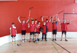 Uczniowie ubrani na czerwono pozują do zdjęcia z kijami do unihokeja. Uczestniczyli w zawodach Mistrzoswa Łodzi w unihokeju dla chłopców - Szkoła Podstawowa nr 6 w Łodzi 27 października 2025 r.
