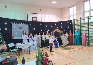 Wspólne kolędowanie podczas Jasełek. Na scenie, anioły, pasterze, królowie, Maryja i Józef ,a także mama i córka.