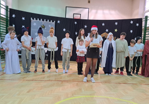 Wszyscy aktorzy zgromadzeni na scenie a przed nimi uczennica klasy VIII przedstawicielka Samorządu Uczniowskiego składa życzenia wszystkim zgromadzonym