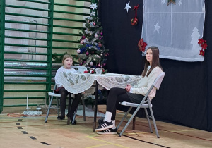 Mama i córka podczas przedstawienia siedzą przy nakrytym stole wigilijnym i rozmawiają o tym jak to było tysiące lat temu