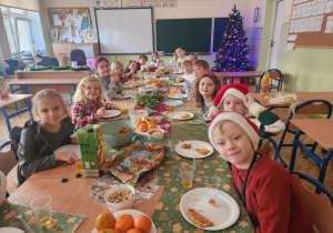 Klasa pierwsza siedzi przy stołach podczas swojej wigilii
