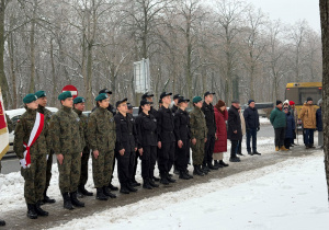 Park w zimowej scenerii na jego tle stoją żołnierze, policjanci oraz mieszkańcy osiedla, którzy przyszli oddać hołd dawnym mieszkańcom osiedla