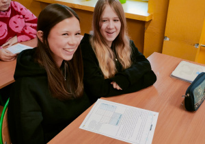 Uśmiechnięte uczennice rozwiązują zagadkę logiczną