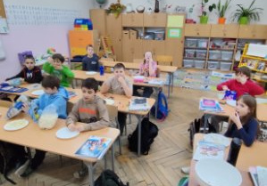 Uczniowie oglądają film na tablicy multimedialnej i zajadają się popcornem