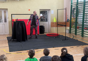 Dzieci siedzą zaciekawione i obserwują co robi Pan Bańka - a on właśnie zrobił bańkę z dymem w środku i trzyma ją na ręku