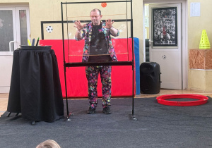 Pan Bańka tworzy bankowe obrazy za pomocą metalowej sztalugi, płynu i dwóch sznurków