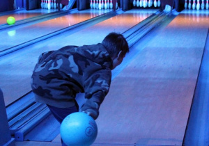 Chłopiec na kręgielni rzuca kulą do celu