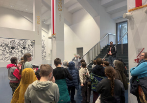 Powitanie na stadionie miejskim im. Władysława Króla. Pan, który nas oprowadza stoi na schodach i opowiada i przy okazji przedstawia zasady obowiązujące na stadionie.