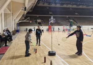 Dzieci na hali sportowej MOSiR, dzieci trzymają w ręku rakietki i odbijają piłeczkę tenisową, która jest przytwierdzona do gumki