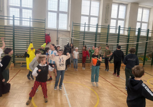 Sala gimnastyczna, wszyscy uczestnicy bawią się w rytm muzyki, tańczą i skaczą.