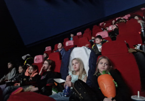 Sala kinowa, uczestnicy siedzą na fotelach kinowych wpatrzeni w ekran