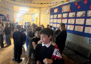 Uczniowie na korytarzu szkolnym podczas zabawy karnawałowej utworzyli ,,pociąg" i bawią się w rytm muzyki