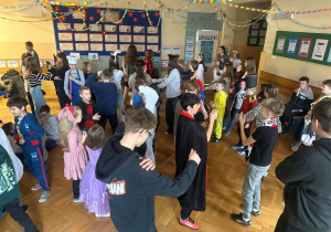 Uczniowie na korytarzu szkolnym podczas zabawy karnawałowej, tańczą w rytm ,,Macareny"