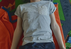 Uczeń klasy III leży na ręczniku na oczach ma plastry zielonego ogórka