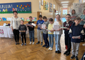 Na zdjęciu organizatorka konkursu ,,Wiosna w moich oczach" pozuje wraz z wyróżnionymi uczniami klas 1-3. Uczniowie mają dyplomy oraz nagrody.