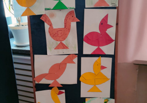 Kolorowe kury geometryczne wykonane przez uczniów klasy V, wywieszone na parawanie na korytarzu klas starszych