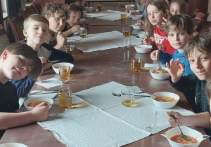Uczniowie na stołówce podczas obiadu, zajadają się pyszną zupą pomidorową.