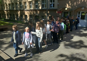 Uczniowie ustawieni w parach przed szkołą przygotowani by ruszyć na przystanek.