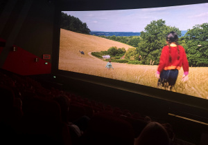 Ekran kina, film pt. ,,Drzewo magii". Na ekranie bohaterka filmu na polu w oddali drzewa.