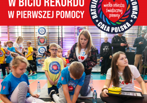 Plakat promujący Bijemy rekord w resuscytacji krążeniowo-oddechowej. Dzieci wraz z nauczycielem przy fantomach. plakat w kolorze czerwonym.