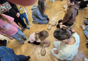 Uczniowie szkoły zgromadzeni na korytarzu, dzieci przy fantomach